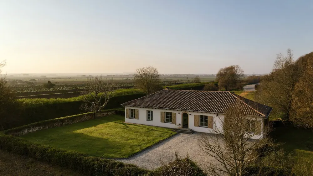 Vue aérienne d'une maison individuelle dans la campagne française, en fin d'après-midi d'hiver.